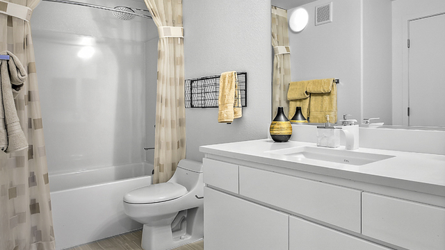 Evolve Apartments - Bathroom with White Furnishings, Toilet, Shower, and Mirror.