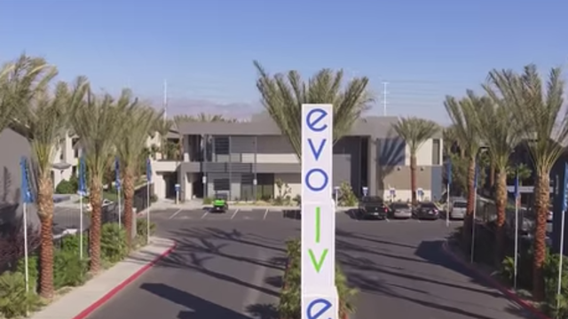 Evolve Apartments - Entranceway with Sign, Palm Trees, and Front Office